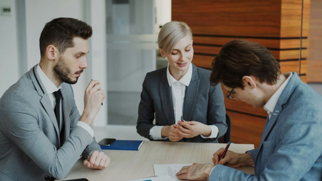 Ba người trao đổi và ký tài liệu tại bàn làm việc